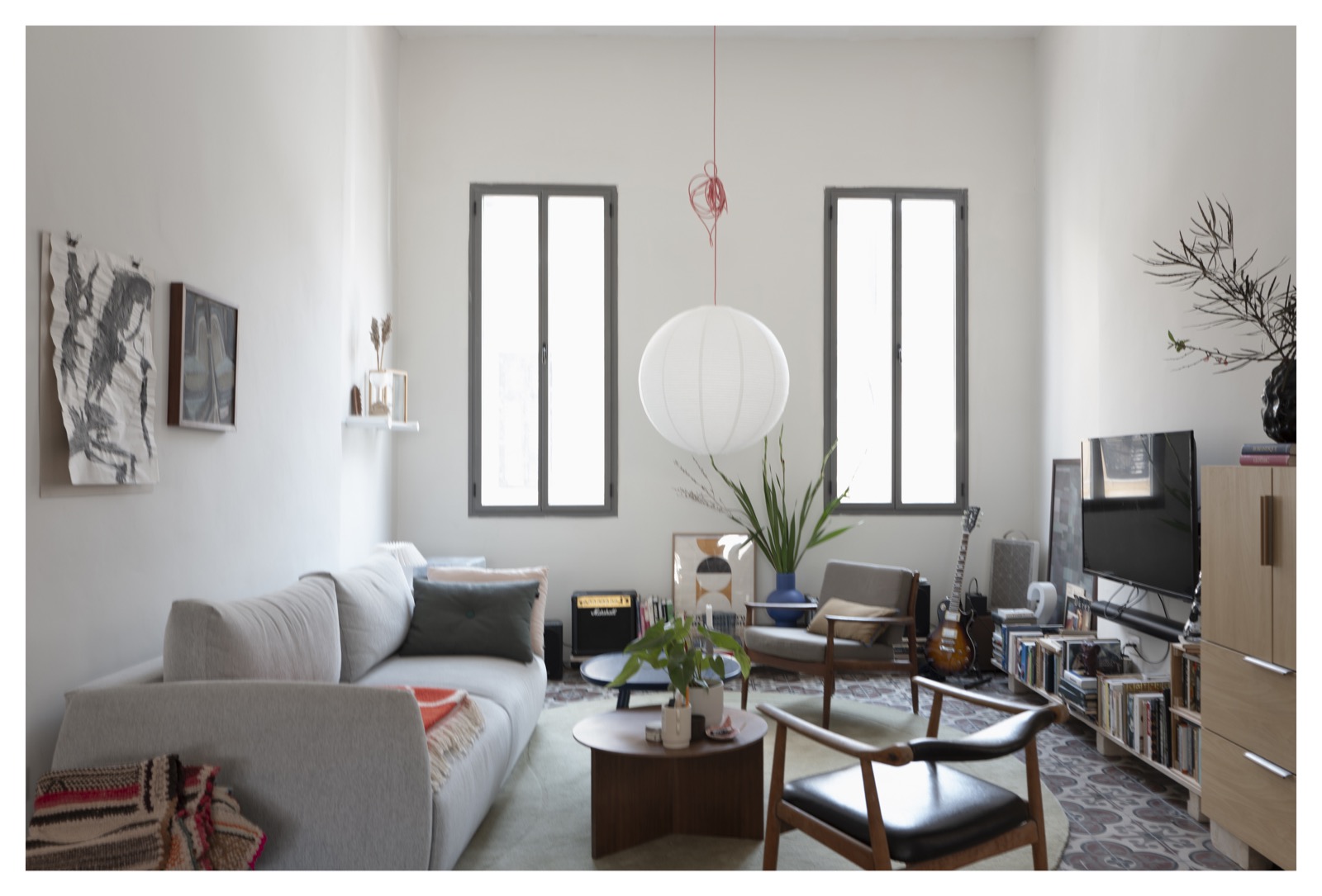 Modern living room interior with tall arched windows, paper globe pendant lamp, curved sofa and midcentury wooden chairs, Tel Aviv — interior architecture photography by STAS PRO