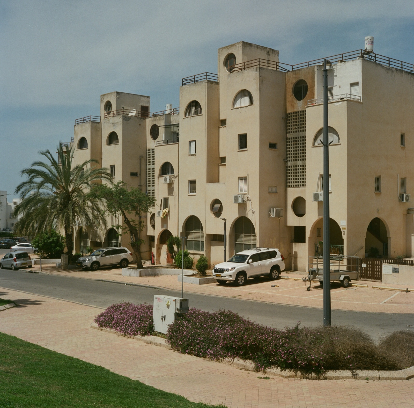 Postmodern beige stucco residential complex with arched arcades and circular rooftop pavilions, Ashkelon, Israel — architectural photography by STAS PRO