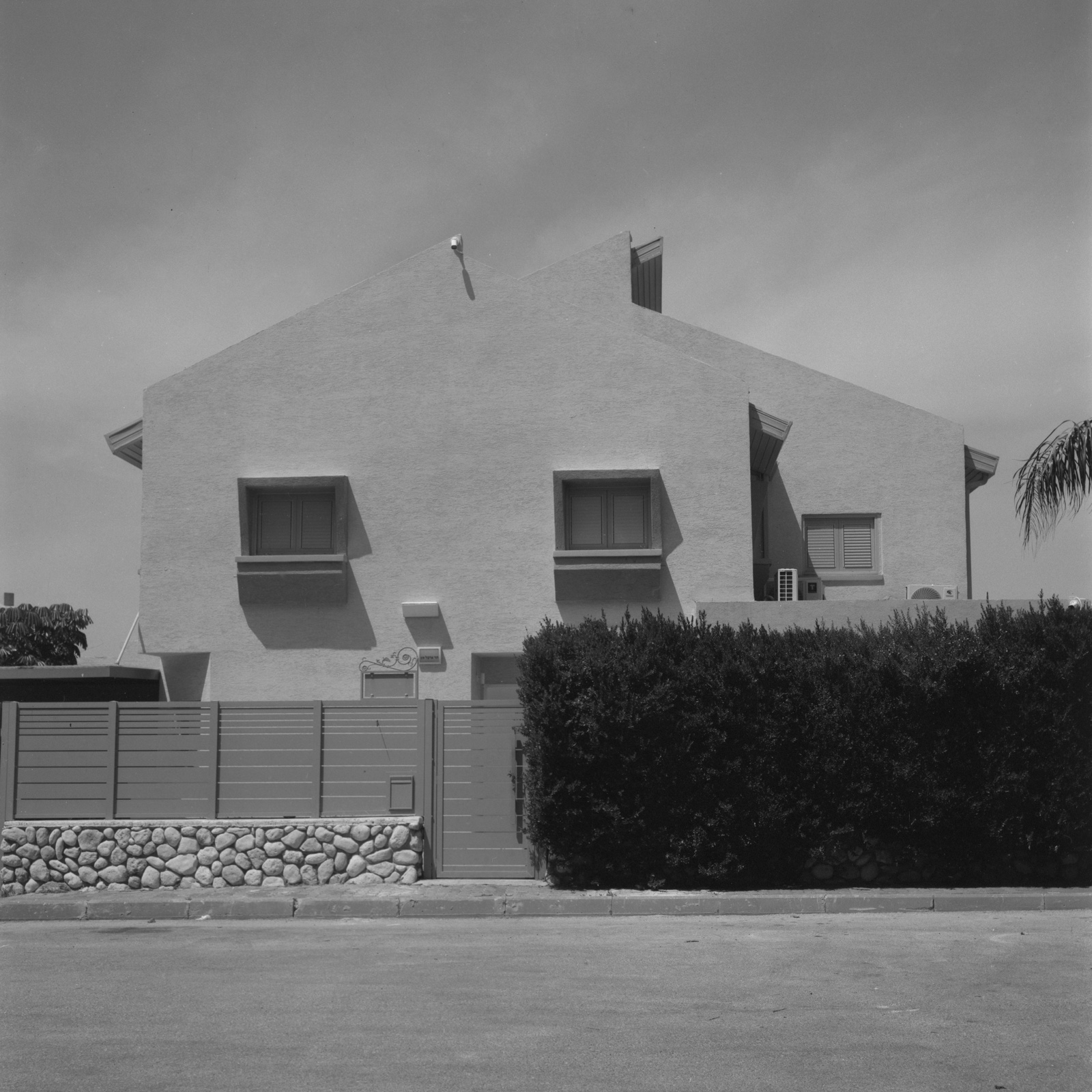Black-and-white study of a gabled white-stucco modernist residence with angular roofline, Ashkelon — architectural photography by STAS PRO