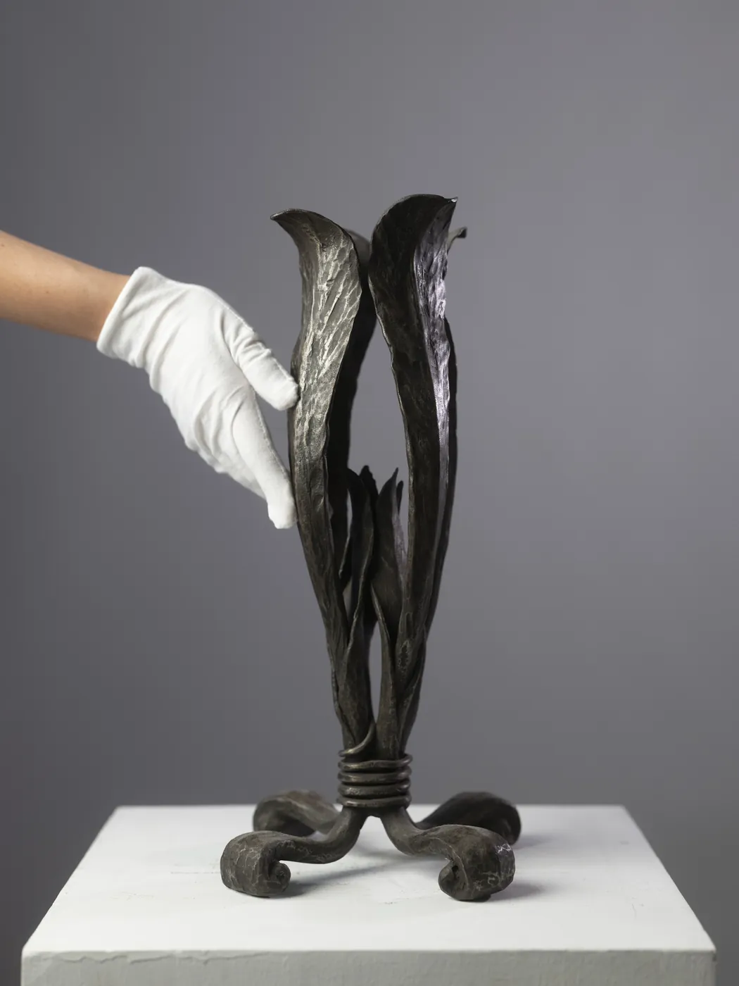 Bronze flower sculpture steadied by a gloved hand. Object photography by STAS PRO