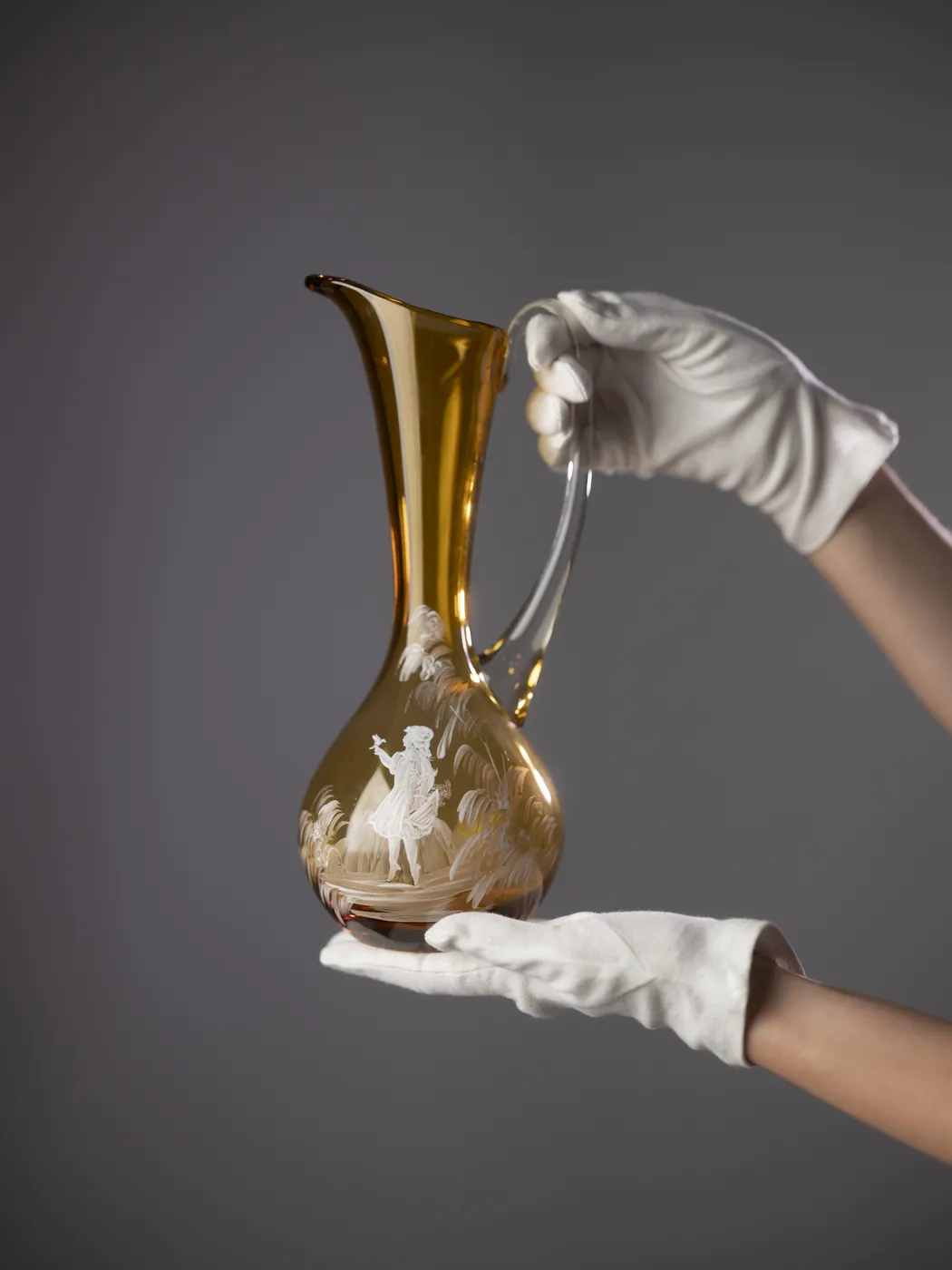 Gilded glass jug held in gloved hands. Photograph by STAS PRO