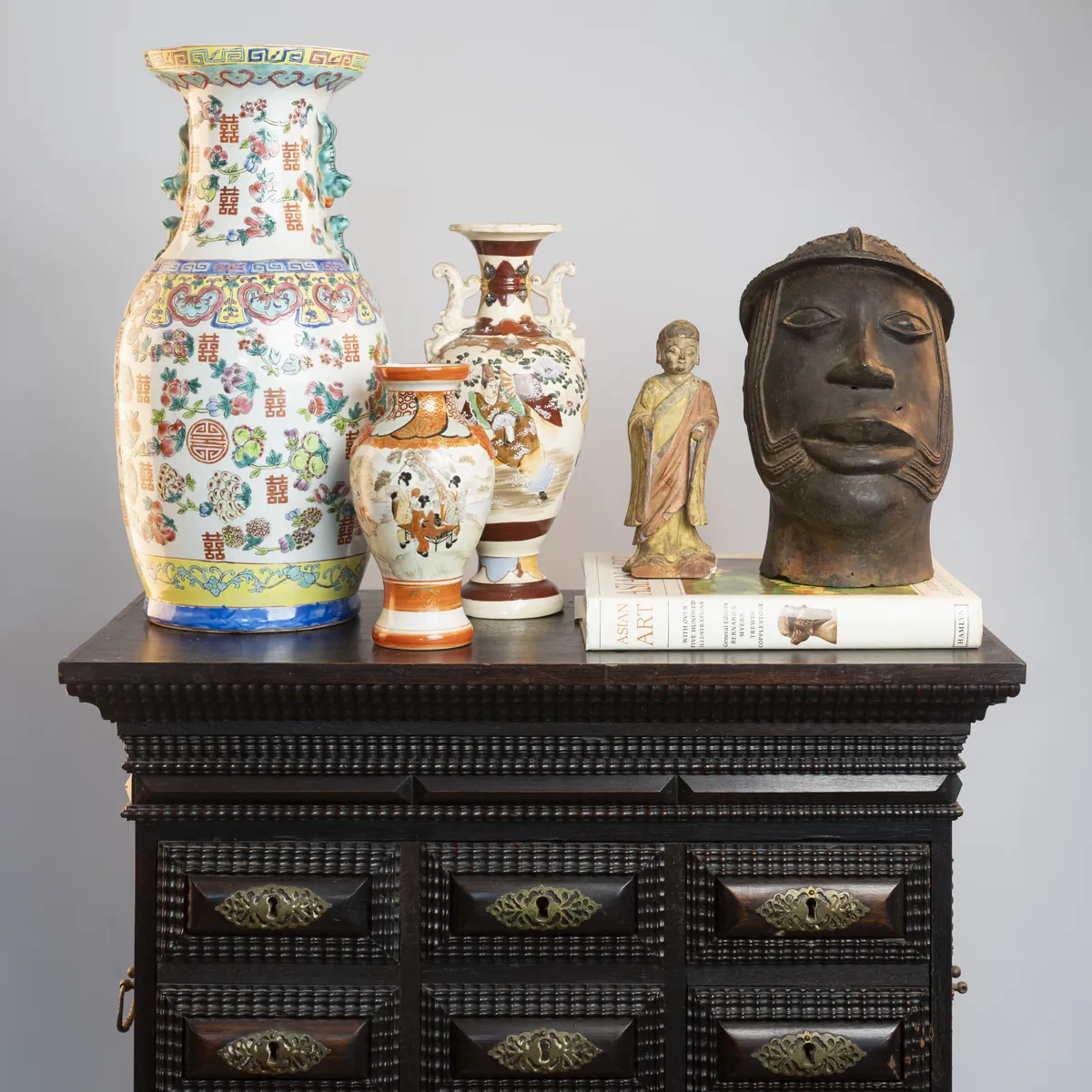 Painted porcelain vases and a bronze head on a carved cabinet. Photograph by STAS PRO