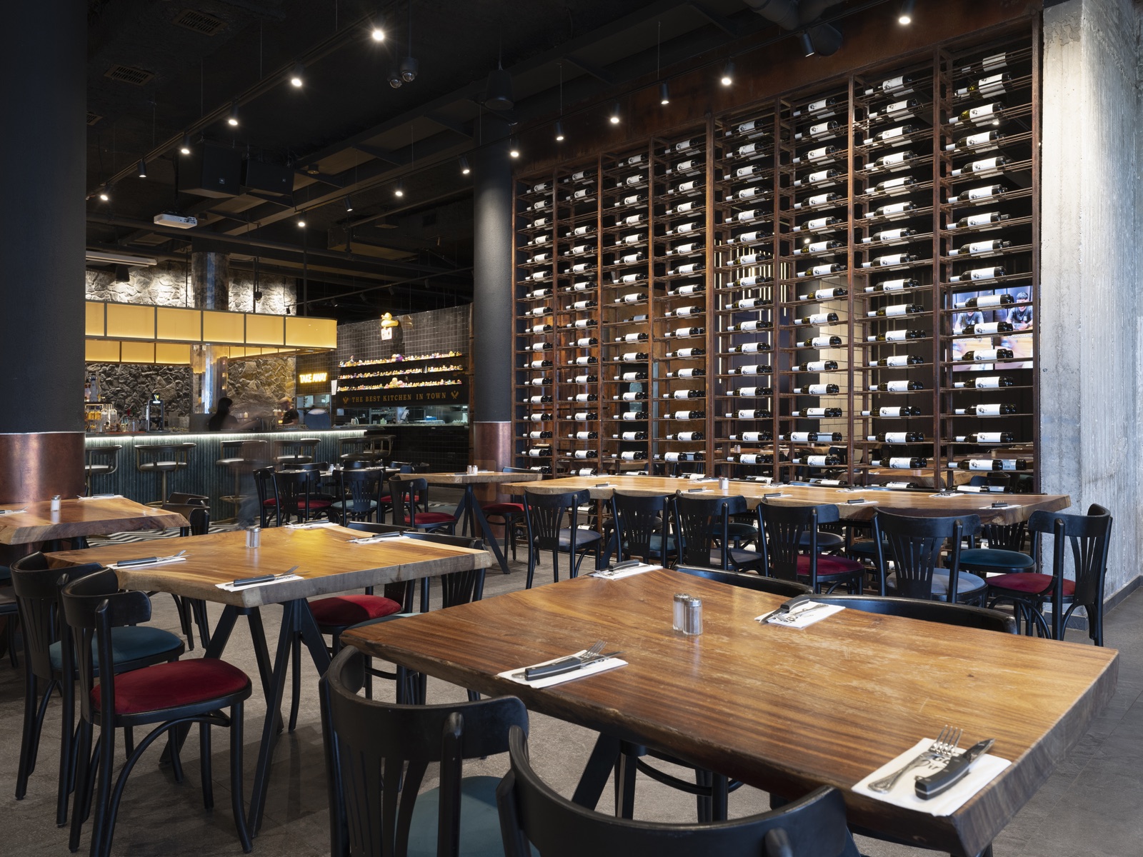 Dining room with live-edge wooden tables and a full-height steel wine wall at Ruben restaurant, Ashkelon. Interior photography by STAS PRO